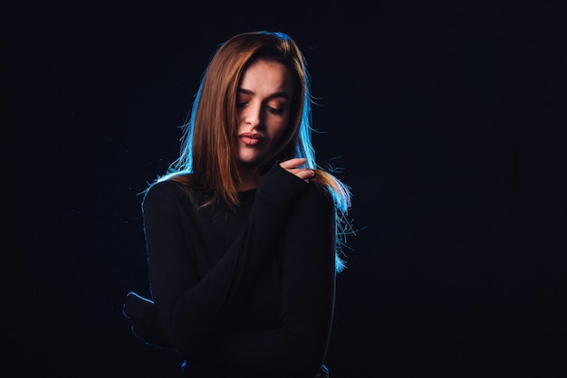 Foto retrato de una hermosa mujer joven con suéter negro sobre fondo negro