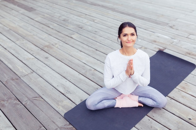 Retrato de hermosa mujer joven trabajando en la naturaleza haciendo ejercicios de yoga y pilates