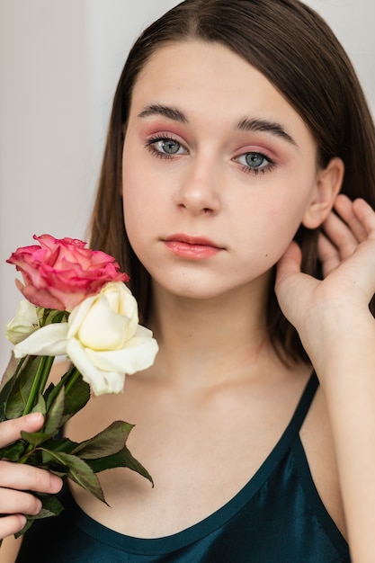 Retrato de hermosa mujer morena con flores. Foto de moda, niña bonita con rosa rosa