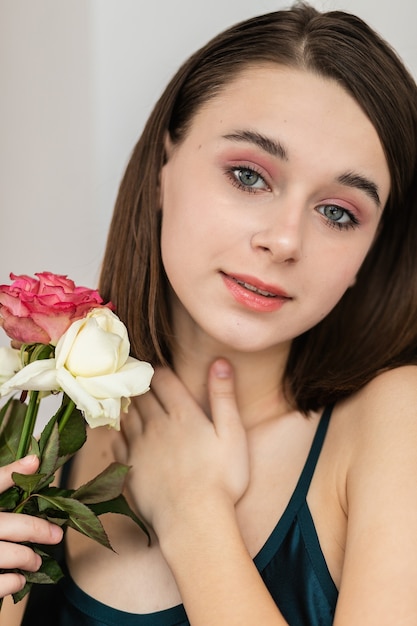 Retrato de hermosa mujer morena con flores. Foto de moda, niña bonita con rosa rosa