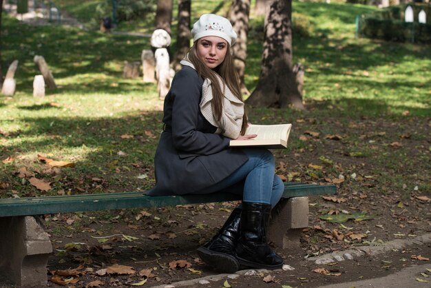 Retrato de una hermosa mujer morena leyendo un libro en el parque de otoño