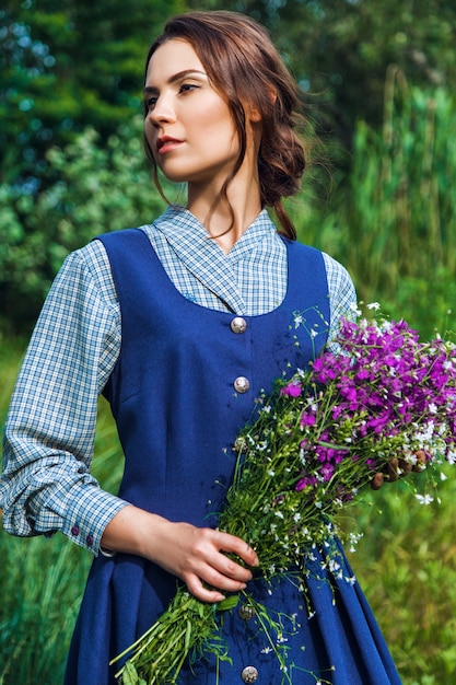 Retrato de una hermosa mujer morena con vestido azul en el campo