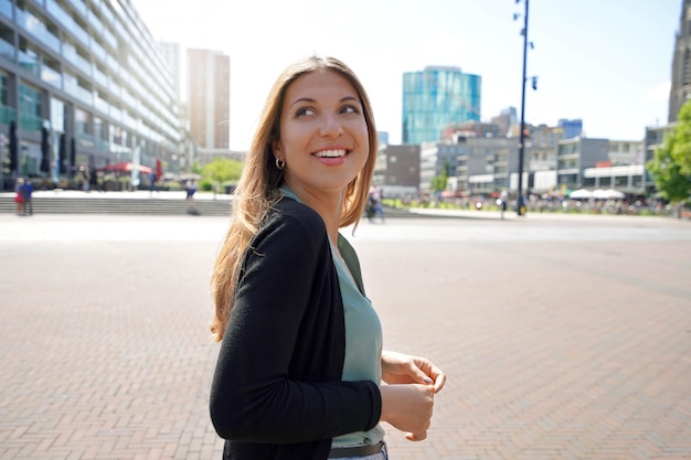 Retrato de una hermosa mujer multiétnica caminando en la ciudad de Rotterdam con arquitectura moderna en Holanda