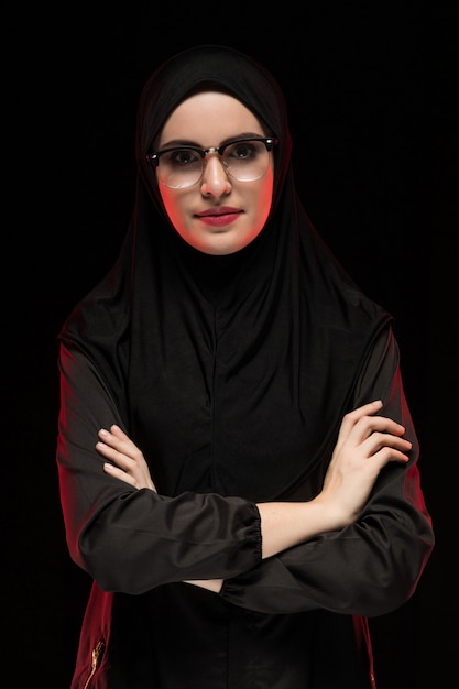 Retrato de hermosa mujer musulmana joven moda vistiendo hiyab negro y gafas concepto de moda posando