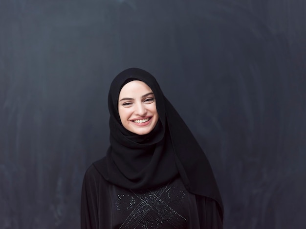 Retrato de una hermosa mujer musulmana vestida de moda con hiyab frente a una pizarra negra que representa la moda islámica moderna y el concepto Ramadan Kareem.