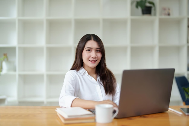 Retrato de una hermosa mujer de negocios asiática en el escritorio de la oficina con computadora portátil en la oficina