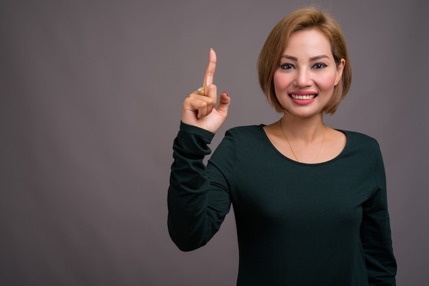 Retrato de hermosa mujer de negocios contra la pared gris