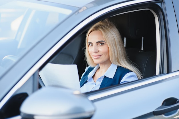 Retrato de una hermosa mujer de negocios madura conduciendo un camión sentado detrás del volante mirando a la cámara y sonriendo