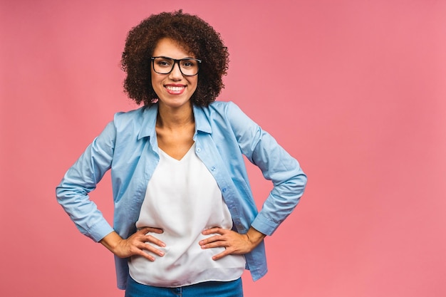 Foto retrato de una hermosa mujer de negocios negra afroamericana positiva que se encuentra aislada sobre un fondo rosa signo ok