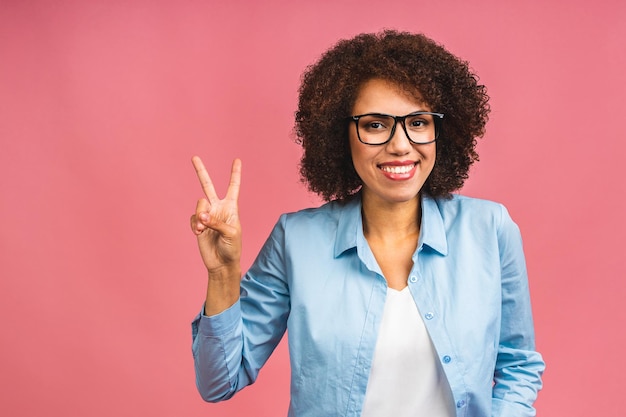 Retrato de una hermosa mujer de negocios negra afroamericana positiva que se encuentra aislada sobre un fondo rosa