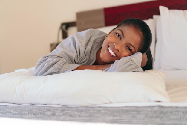 Un retrato de una hermosa mujer negra acostada en la cama, mirando a la cámara.