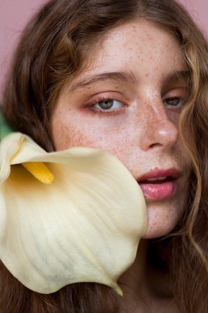 Retrato de hermosa mujer pecosa sosteniendo una flor blanca