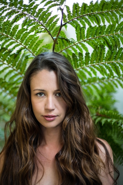 Retrato de hermosa mujer de pie al aire libre contra las plantas verdes