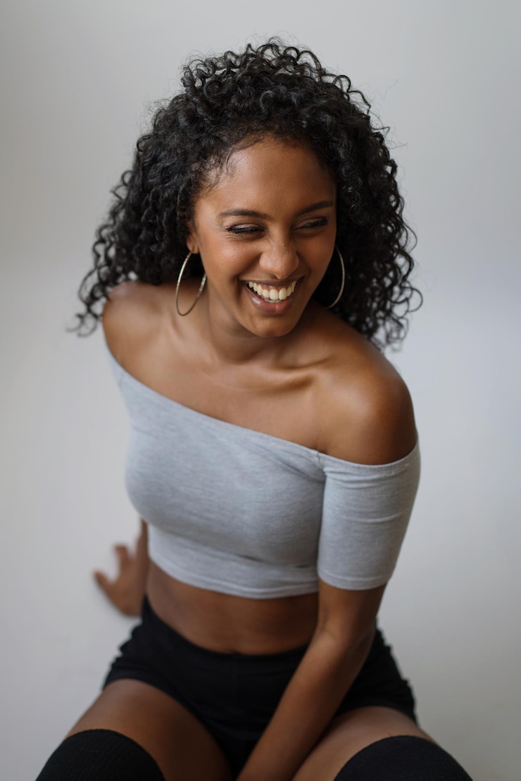 Foto retrato de una hermosa mujer de piel oscura con el pelo largo y rizado sonriendo