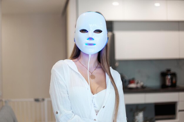 Foto retrato de una hermosa mujer realizando un procedimiento de mascarilla facial de terapia de luz en casa