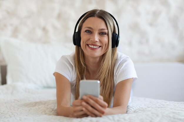 Retrato de hermosa mujer rubia con auriculares y teléfono inteligente