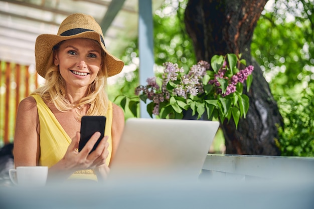 Retrato de una hermosa mujer rubia elegante con una sonrisa radiante sentada en la terraza