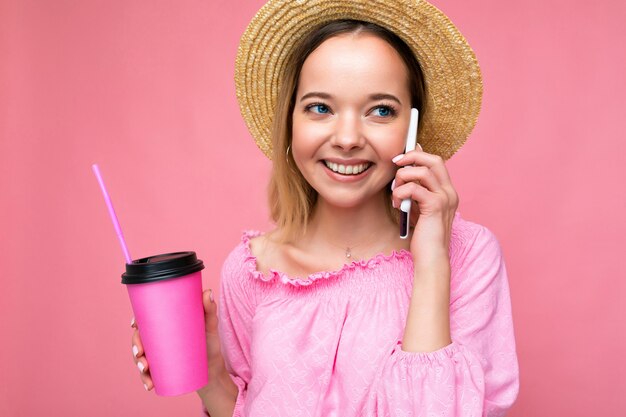 Retrato de hermosa mujer rubia joven emocional positiva vistiendo blusa rosa y sombrero de paja