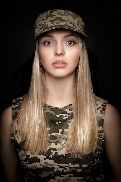 Foto retrato de una hermosa mujer rubia soldados en traje militar sobre fondo negro