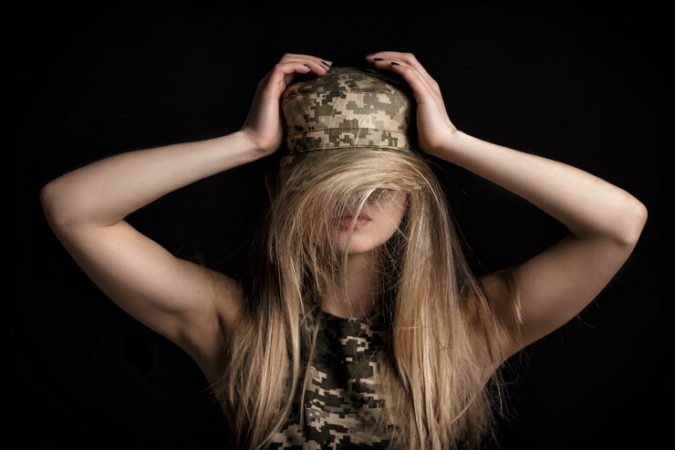 Retrato de una hermosa mujer rubia soldados en traje militar sobre fondo negro