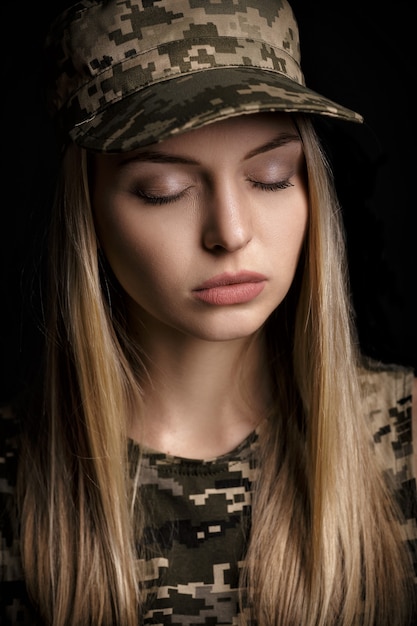 Retrato de una hermosa mujer rubia soldados en traje militar sobre fondo negro