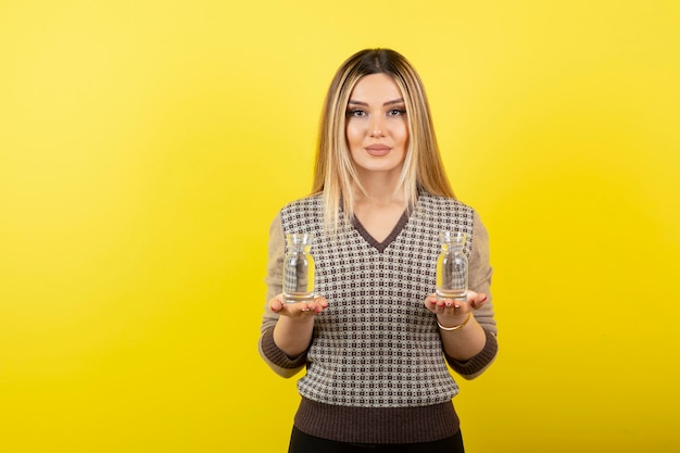 Retrato de hermosa mujer rubia sosteniendo dos vasos de agua sin gas.