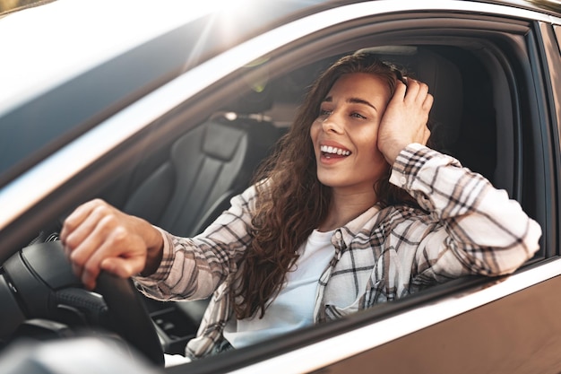 Retrato de una hermosa mujer sonriente en un coche mirando por la ventana de cerca