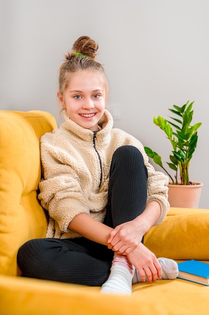 Retrato de una hermosa niña adolescente feliz en un sofá amarillo