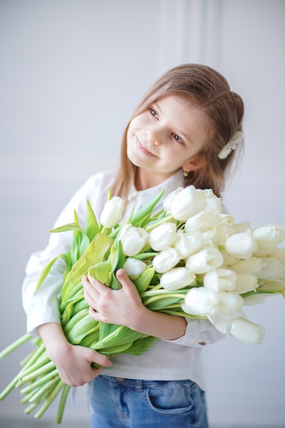 Retrato de hermosa niña bonita con tulipanes de flores blancas