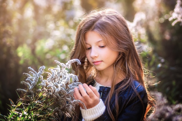 Retrato de una hermosa niña con cabello largo en la naturaleza en verano