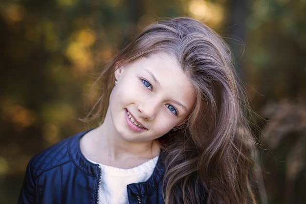 Retrato de una hermosa niña con cabello largo en la naturaleza en verano