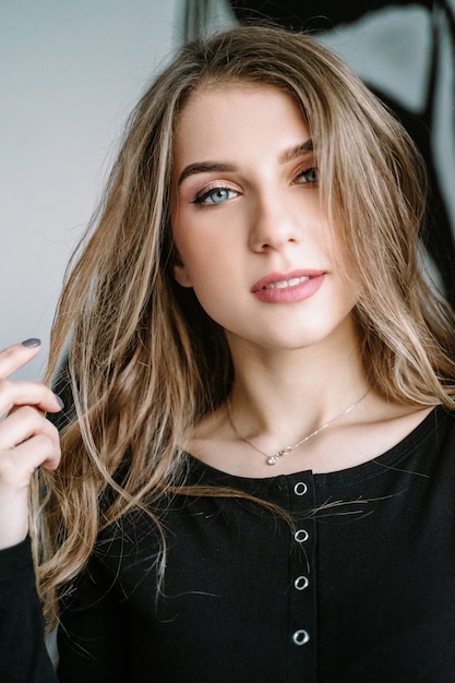 Retrato de una hermosa niña con cabello largo rubio en una camiseta negra