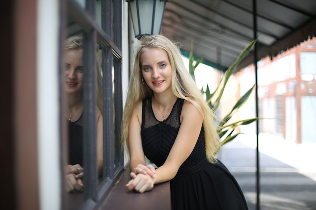 Retrato de hermosa niña de cabello rubio en vestido negro como retrato de moda al aire libre