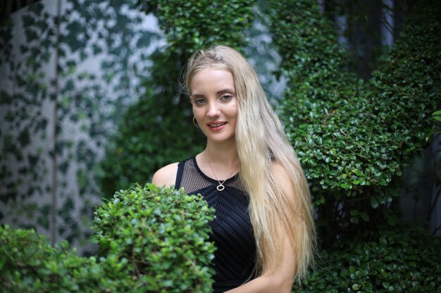 Retrato de hermosa niña de cabello rubio en vestido negro como retrato de moda al aire libre