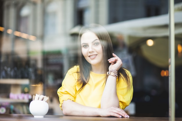 Retrato de una hermosa niña en un café con vistas a la calle