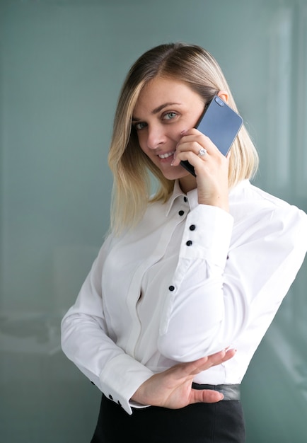 Retrato de una hermosa niña con una camisa blanca y una falda negra con teléfono