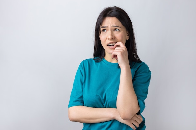 Retrato de una hermosa niña en una camiseta azul mira a un lado con expresión pensativa