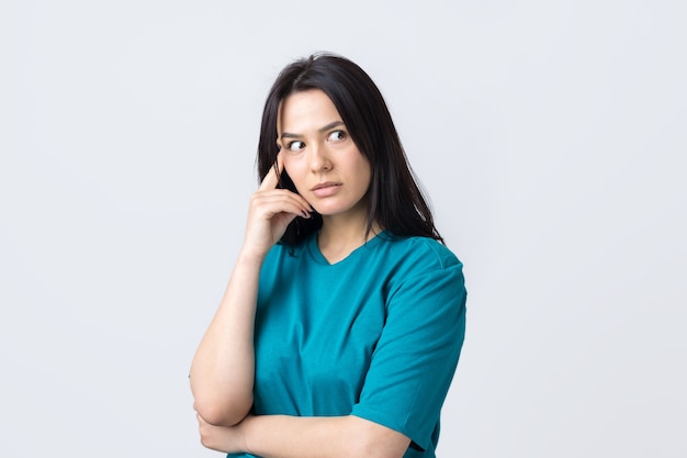 Retrato de una hermosa niña en una camiseta azul mira a un lado con expresión pensativa