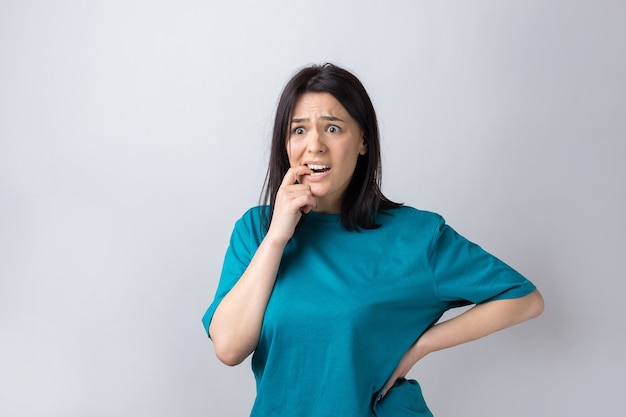 Retrato de una hermosa niña en una camiseta azul mira a un lado con expresión pensativa