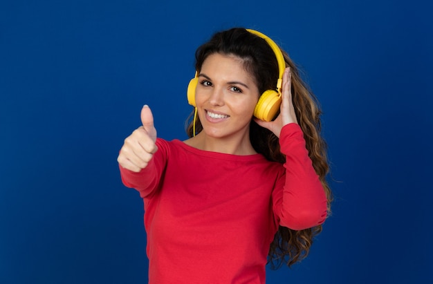 Retrato de hermosa niña caucásica con cabello rizado y auriculares escuchando música aislado en una pared blanca