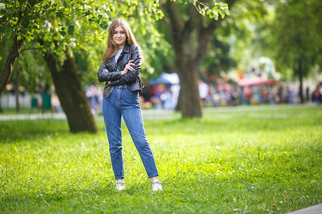 Retrato de una hermosa niña con estilo en el parque de la ciudad en el fondo del bosque verde