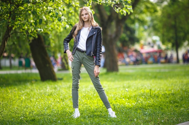 Retrato de una hermosa niña con estilo en el parque de la ciudad en el fondo del bosque verde