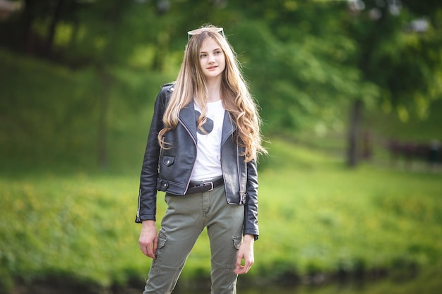 Retrato de una hermosa niña con estilo en el parque de la ciudad en el fondo del bosque verde