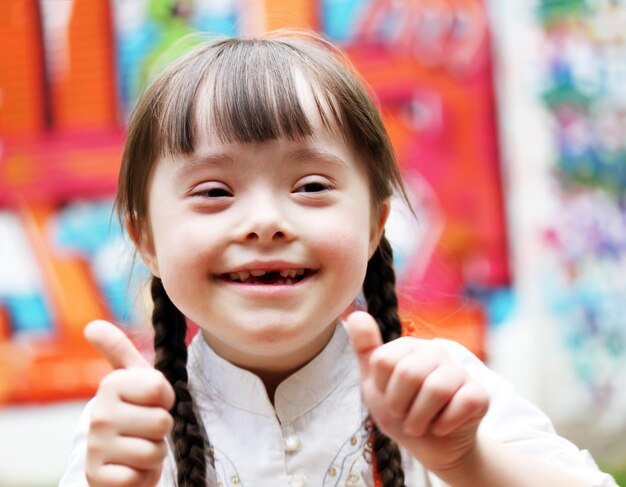 Retrato de una hermosa niña feliz dando pulgares hacia arriba.