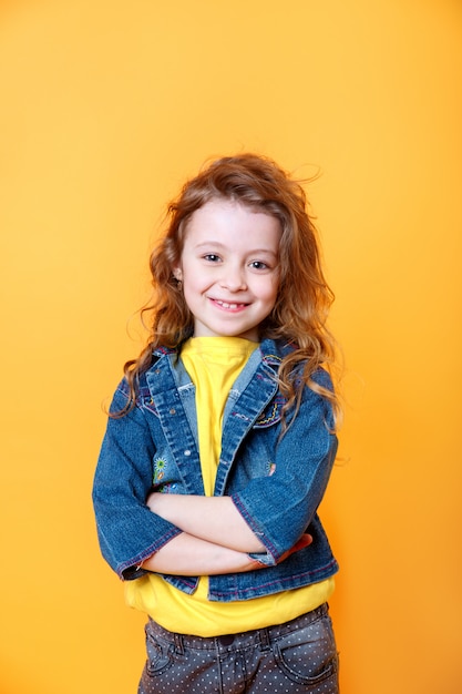 Retrato de hermosa niña feliz rizada sobre fondo naranja