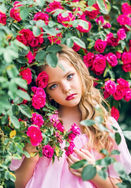 Retrato de una hermosa niña en flores rosas