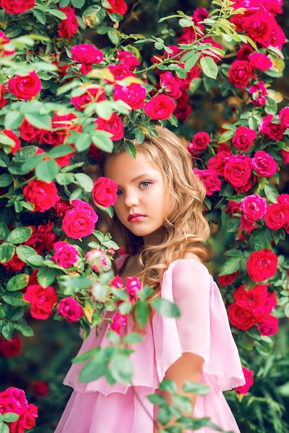 Retrato de una hermosa niña en flores rosas