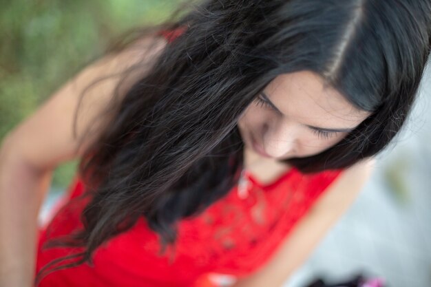 Retrato de una hermosa niña. Hermosa chica morena, retrato en la suave luz del atardecer. Retrato de una joven hermosa con el pelo largo y oscuro y con un vestido rojo.