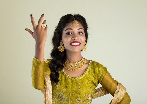 Retrato de hermosa niña india tradicional posando en la pared blanca.