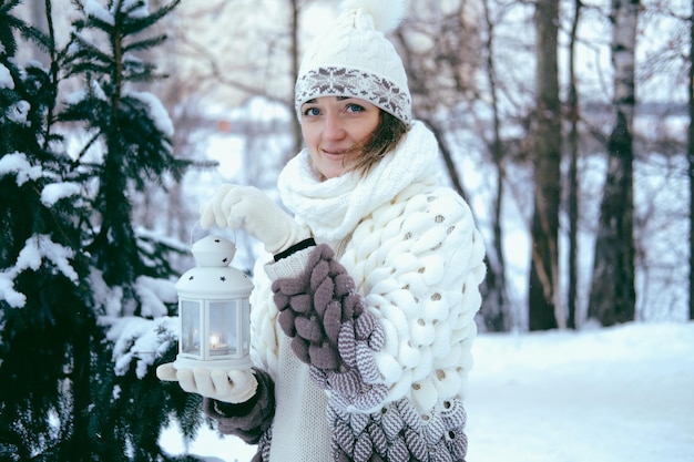 Retrato de una hermosa niña en el invierno en el parque en sus manos sostiene una linterna con velas